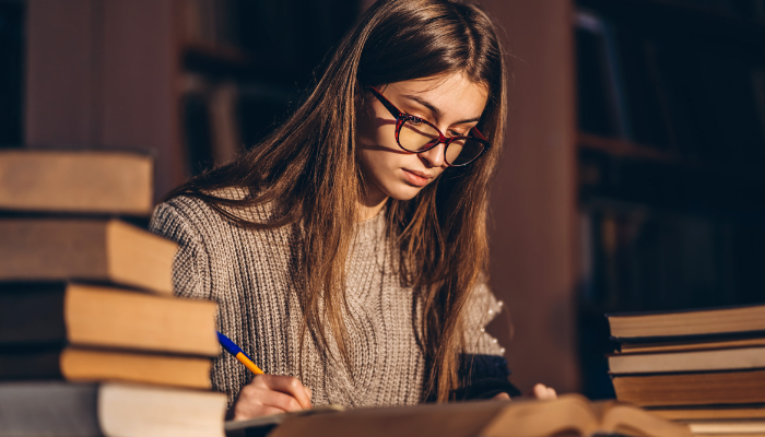 A young woman with glasses is focused on studying