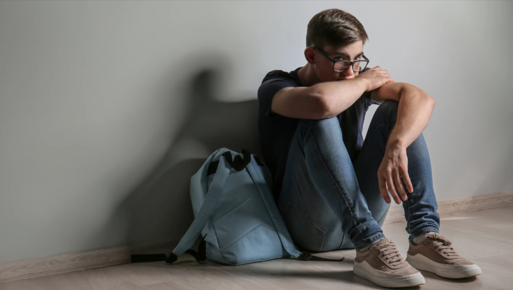 Teenage boy sitting against a wall,