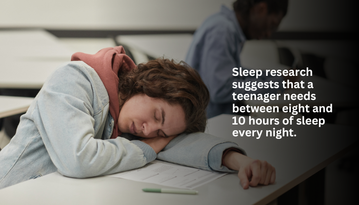 A teenager sleeps on a desk, highlighting the need for 8-10 hours of sleep.