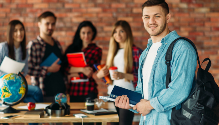 Smiling student with classmates in background, holding books